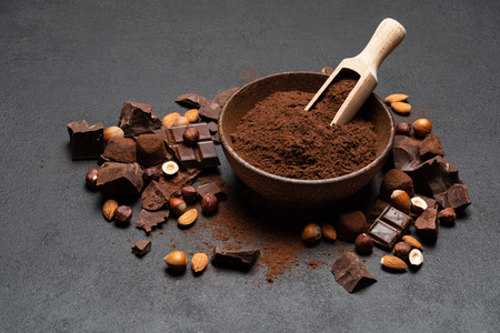 Dark Chocolate chunks, nuts and cocoa powder in wooden bowl on dark concrete backgroundの写真素材