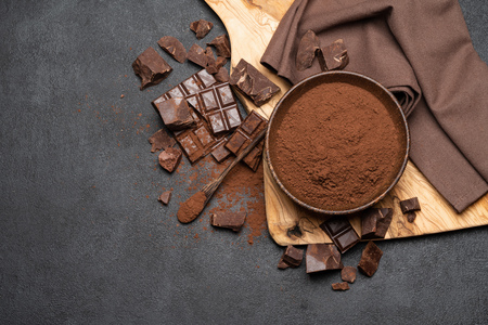 Dark Chocolate chunks and cocoa powder in wooden bowl on dark concrete backgroundの写真素材
