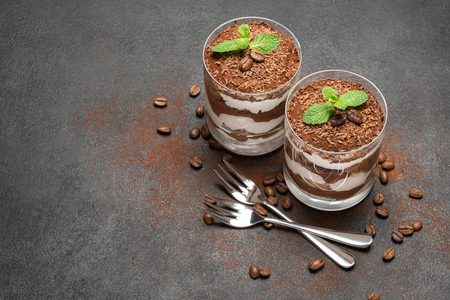 two portions Classic tiramisu dessert in a glass on dark concrete backgroundの写真素材