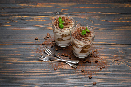 two portions Classic tiramisu dessert in a glass on wooden backgroundの写真素材