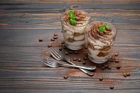 two portions Classic tiramisu dessert in a glass on wooden backgroundの写真素材