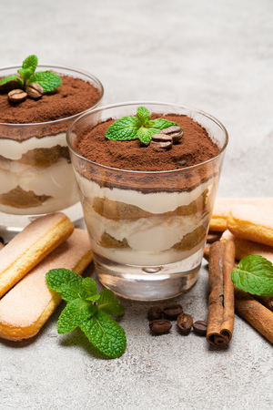Classic tiramisu dessert in a glass and savoiardi cookies on concrete backgroundの写真素材