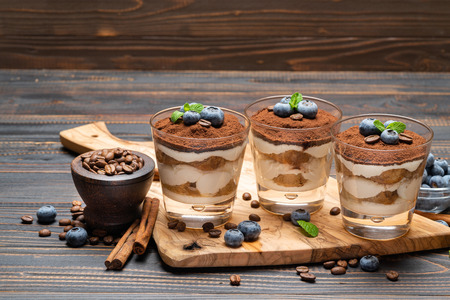 Classic tiramisu dessert in a glass with blueberries on wooden backgroundの写真素材