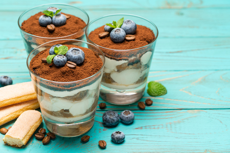 Classic tiramisu dessert in a glass with blueberries on blue wooden backgroundの写真素材