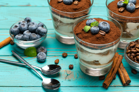 Classic tiramisu dessert in a glass with blueberries on blue wooden backgroundの写真素材