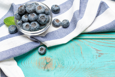 Glass bowl full of fresh blueberries with herbs on wooden backgroundの写真素材