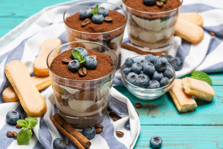 Classic tiramisu dessert in a glass with blueberries on blue wooden backgroundの写真素材