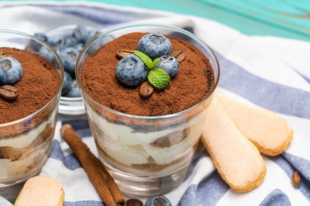 Classic tiramisu dessert in a glass with blueberries on blue wooden backgroundの写真素材