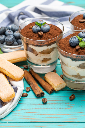 Classic tiramisu dessert in a glass with blueberries on blue wooden backgroundの写真素材