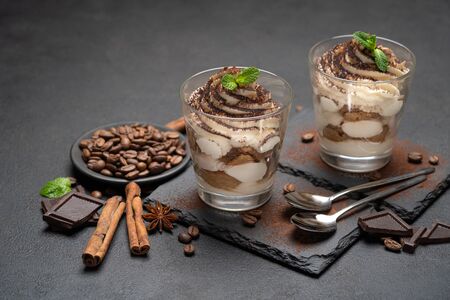 Classic tiramisu dessert in a glass on stone serving board on dark concrete backgroundの写真素材