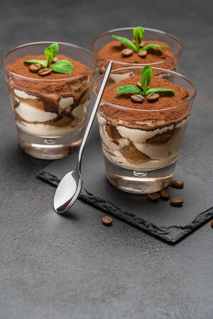 Classic tiramisu dessert in a glass on stone serving board on dark concrete backgroundの写真素材