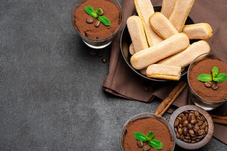 Frame made of Classic tiramisu dessert in a glass and savoiardi cookies on dark concrete backgroundの写真素材
