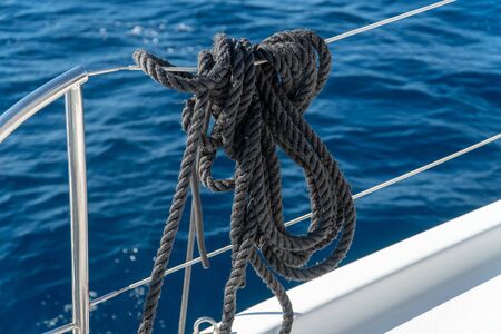 black mooring lines hanging on the reeling on a sailing yachtの写真素材