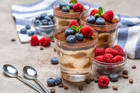 Classic tiramisu dessert with blueberries and raspberries in a glass and napkin on concrete backgroundの写真素材