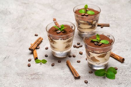 Classic tiramisu dessert in a glass and cinnamon sticks on concrete backgroundの写真素材