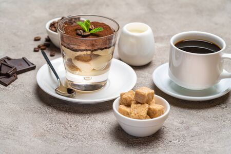 Classic tiramisu dessert in a glass, coffee, chocolate, cream and sugar on concrete backgroundの写真素材