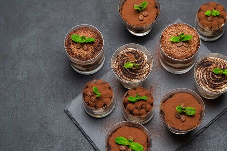 Group of portions of Classic tiramisu dessert in a glass cup on stone board on concrete backgroundの写真素材
