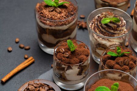 Group of portions of Classic tiramisu dessert in a glass cup on stone board on concrete backgroundの写真素材