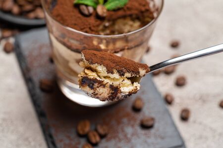 Portion of Classic tiramisu dessert in a glass cup on stone serving board on concrete backgroundの写真素材