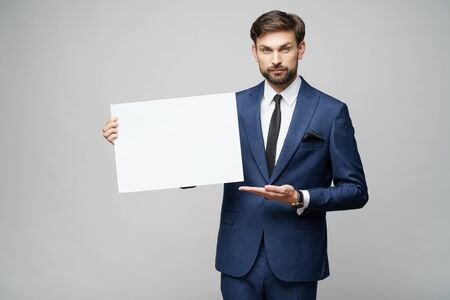 Young businessman holding blank signs over grey backgroundの写真素材