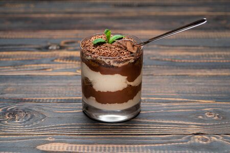 Classic tiramisu dessert in a glass cup on wooden background or table