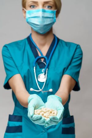 medical doctor nurse woman wearing protective mask and rubber or latex gloves - holding pillsの写真素材