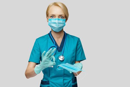 medical doctor nurse woman with stethoscope over light grey background - showing protective maskの写真素材