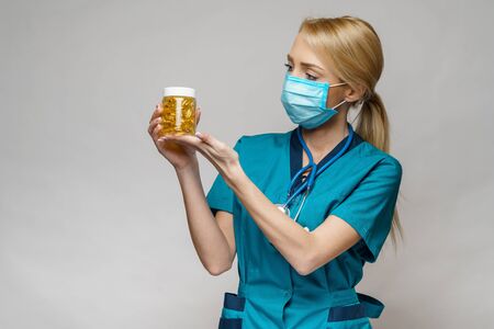 medical doctor nurse woman wearing protective mask and rubber or latex gloves - holding can of pills
