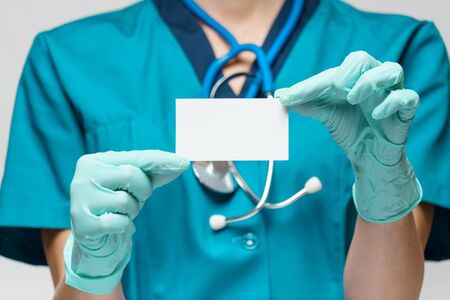medical doctor nurse woman wearing protective mask and gloves - showing blank business card.の写真素材