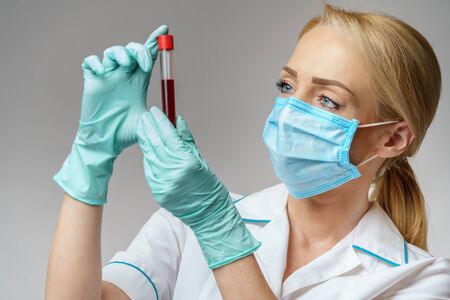 medical doctor nurse woman wearing protective mask and gloves - holding virus blood test