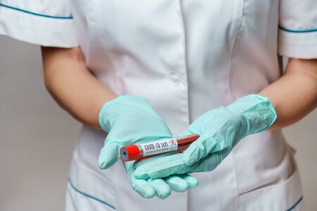 medical doctor nurse woman wearing protective mask and gloves - holding virus blood test