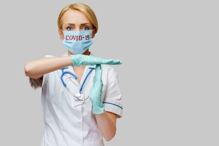 female doctor with stethoscope wearing protective mask and latex gloves over light grey backgroundの写真素材