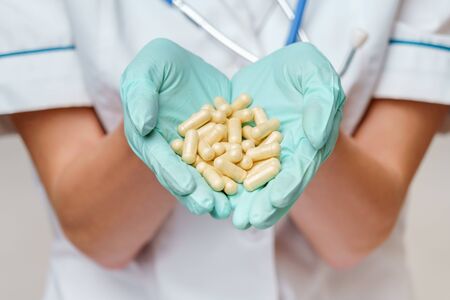 medical doctor nurse woman wearing protective mask and rubber or latex gloves - holding pills