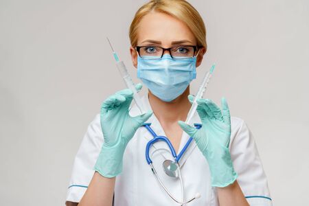 medical doctor nurse woman wearing protective mask and gloves - holding syringeの写真素材