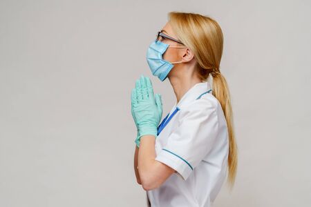 medical doctor nurse woman wearing protective mask and latex gloves - praying nad hoping gestureの写真素材