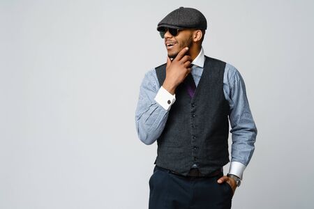 African-American man wearing cap, shirt and tie portrait over grey backgroundの写真素材