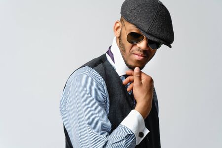 African-American man wearing cap, shirt and tie portrait over grey background
