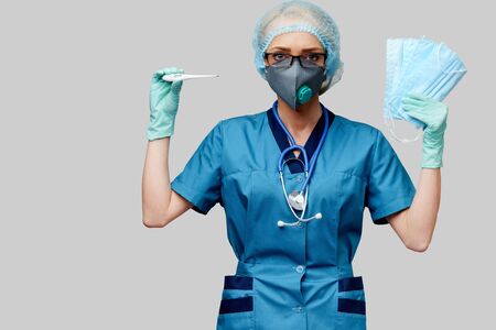 female doctor with stethoscope wearing protective mask and latex gloves over light grey background holding thermometerの写真素材