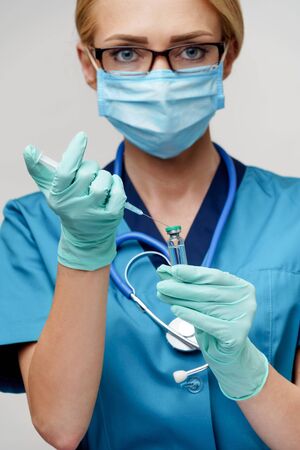 medical doctor nurse woman wearing protective mask and gloves - holding syringeの写真素材