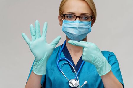 medical doctor nurse woman with stethoscope wearing protective mask and rubber or latex gloves showing at herselfの写真素材