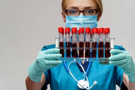 medical doctor nurse woman wearing protective mask and gloves - holding rack with virus blood testsの写真素材