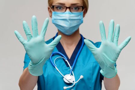 medical doctor nurse woman with stethoscope wearing protective mask and rubber or latex gloves showing at herselfの写真素材