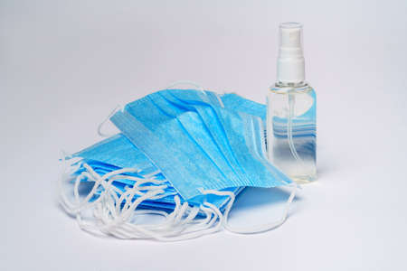 bottle of lotion, sanitizer or liquid soap and protective mask over light grey background