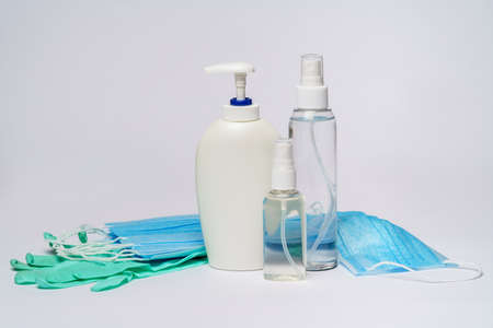 bottle of lotion, sanitizer or liquid soap, rubber latex gloves and protective mask over light grey backgroundの写真素材