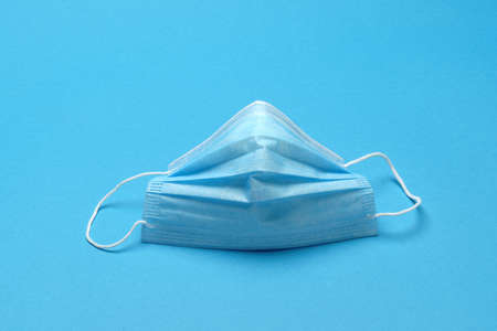 Disposable blue medical face mask on blue backgroundの写真素材