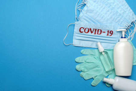 Stack of Disposable blue medical face masks with COVID-19 sign, rubber latex gloves and alcohol hand sanitizer antiseptic on blue backgroundの写真素材