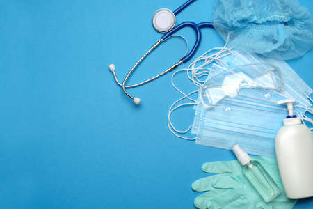 Stack of Disposable blue medical face masks, rubber latex gloves, goggles, stethoscope and alcohol hand sanitizer antiseptic on blue backgroundの写真素材