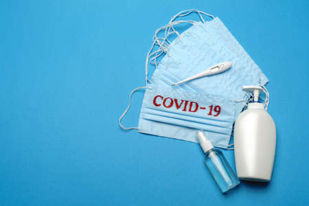 Stack of Disposable blue medical face masks with COVID-19 sign and alcohol hand sanitizer antiseptic...