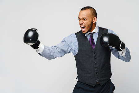 Angry upset young man office worker, business employee, fists in air with boxing gloves, open mouth yelling and shouting, negative emotion facial expression feelingの写真素材