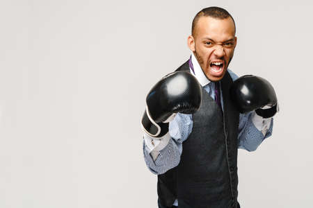 Angry upset young man office worker, business employee, fists in air with boxing gloves, open mouth yelling and shouting, negative emotion facial expression feelingの写真素材